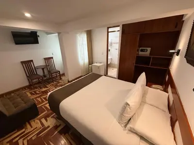 a bedroom with a large bed and two chairs at Awki´s Dream Hotel in Cusco