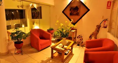a living room with two chairs and a table and flowers at Awki´s Dream Hotel in Cusco