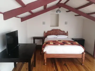 a bedroom with a bed with a desk and a tv at Departamentos Cusco in Cusco