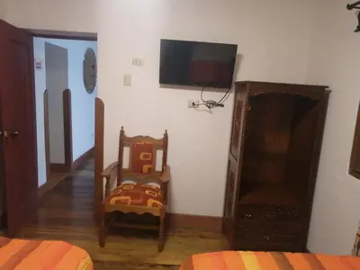 a room with a bed and a chair and a flat screen tv at Departamentos Cusco in Cusco