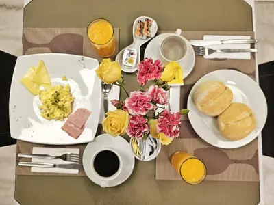 a table topped with plates of breakfast food and flowers at Inkari Apart Hotel in Lima