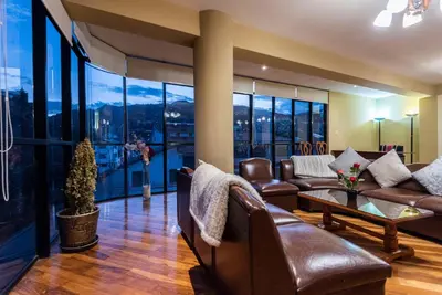 a living room with leather furniture and large windows at Espacioso confortable apartamento familia in Cusco