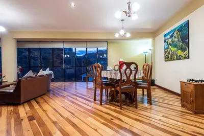 a dining room and living room with a table and chairs at Espacioso confortable apartamento familia in Cusco
