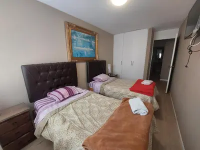 a bedroom with two beds and a bench in it at Apartamento PARDO CCA in Lima