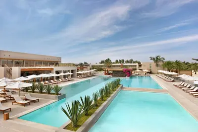 a hotel pool with lounge chairs and umbrellas at The Legend Paracas Resort, a Destination by Hyatt Hotel in Paracas