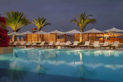 a resort pool with chairs and umbrellas at night at The Legend Paracas Resort, a Destination by Hyatt Hotel in Paracas