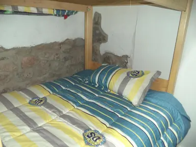 a bed with a striped comforter and a pillow at Gringo's Wasi in Cusco