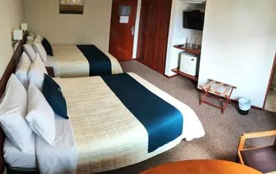a hotel room with two beds and a table at Hotel Carmel in Lima