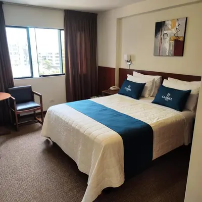 a hotel room with a large bed with blue pillows at Hotel Carmel in Lima
