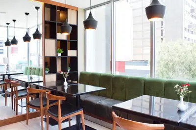 a restaurant with tables and a green couch at Habitat Hotel in Lima