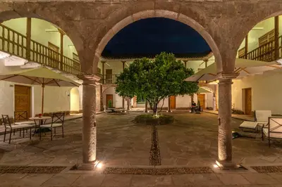 a courtyard with a tree and tables and umbrellas at Hotel La Casona De Yucay Valle Sagrado in Urubamba