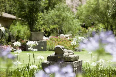 a statue of a bear sitting on a rock in a garden at Hotel La Casona De Yucay Valle Sagrado in Urubamba