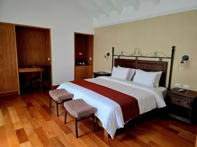 a bedroom with a large bed with two chairs at Hotel La Casona De Yucay Valle Sagrado in Urubamba