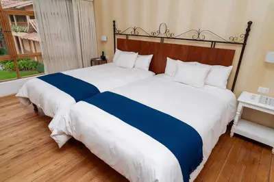 two beds with blue and white sheets in a bedroom at Hotel La Casona De Yucay Valle Sagrado in Urubamba