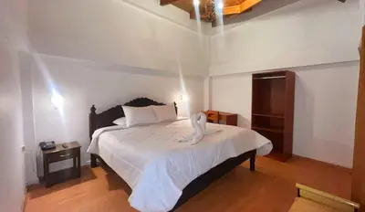 a bedroom with a bed with a white bedspread at SAN BLAS PLAZA INn in Cusco