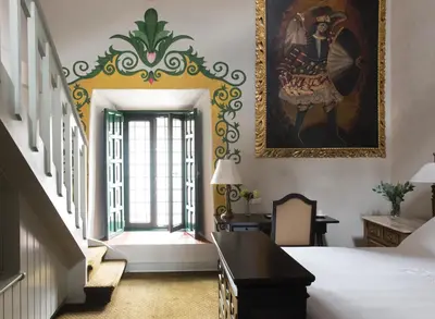 a bedroom with a bed and a painting on the wall at Monasterio, A Belmond Hotel, Cusco in Cusco