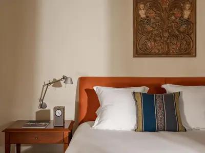 a bedroom with a bed and a nightstand with a clock at Rio Sagrado, A Belmond Hotel, Sacred Valley in Urubamba