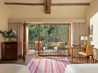 a living room with a sliding glass door leading to a patio at Rio Sagrado, A Belmond Hotel, Sacred Valley in Urubamba
