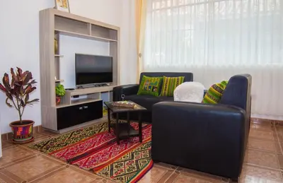 a living room with two chairs and a flat screen tv at Boutique Amaru Wasi in Cusco
