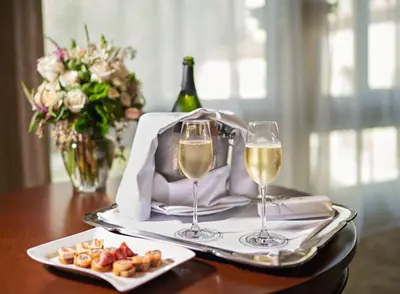 a table with two glasses of wine and a plate of food at Country Club Lima Hotel – The Leading Hotels of the World in Lima