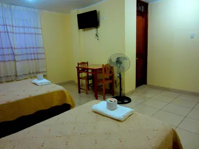 a room with two beds and a table with a fan at Sandel in Barranca