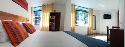a bedroom with a bed with orange and blue pillows at Mantu Boutique in Machu Picchu