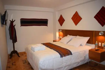 a bedroom with a large bed with white sheets at Mantu Boutique in Machu Picchu