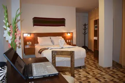 a hotel room with a bed and a desk with a laptop at Mantu Boutique in Machu Picchu