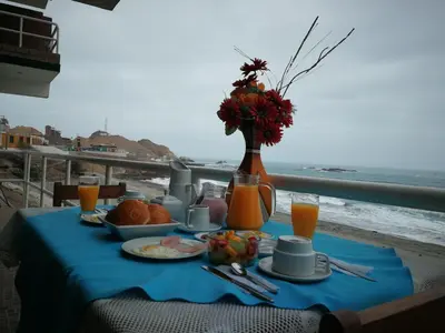 a table with a blue table cloth with food and a view of the ocean at Meflo Playa Grande in Chala