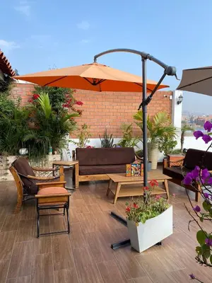 a patio with an umbrella and chairs and tables at Prince Hospedaje in Ayacucho