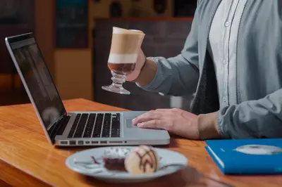 a person sitting at a table with a laptop and a drink at Girasoles Hotel in Lima