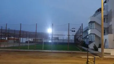 a soccer field behind a fence in front of a building at Condominio Las Terrazas in Asia