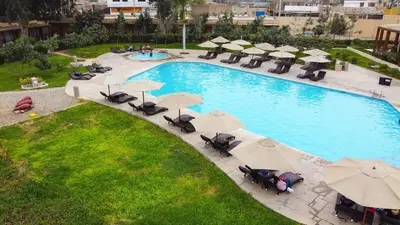 an overhead view of a swimming pool with chairs and umbrellas at Casa Andina Standard Chincha in Chincha Alta