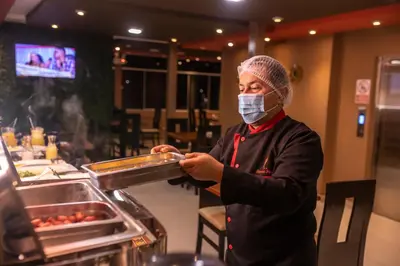 a person wearing a mask preparing food in a restaurant at Hotel Ferré Boulevard in Machu Picchu