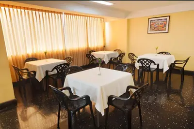a dining room with tables and chairs with white table cloth at Hotel Olaya in Lima