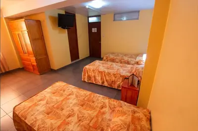 a hotel room with two beds and a flat screen tv at Hotel Olaya in Lima