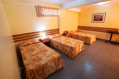 a hotel room with three beds in a room at Hotel Olaya in Lima