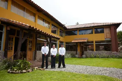 three men standing in front of a yellow building at Willka Rumi in Urubamba