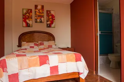 a bedroom with a bed and some pictures on the wall at Hostal Las Fresas Lima Airport in Lima