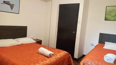a room with two beds and a black door at Qoricancha B&B Cusco in Cusco