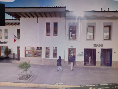 two women walking in front of a white building at Qoricancha B&B Cusco in Cusco