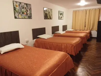 a row of four beds in a hotel room at Qoricancha B&B Cusco in Cusco