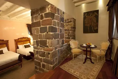 a room with two beds and a stone wall at Aranwa Cusco Boutique Hotel in Cusco
