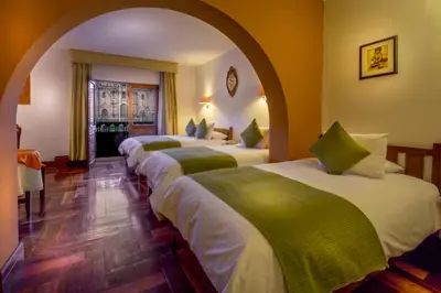 a row of four beds in a hotel room at Katari Plaza Cusco El Virrey in Cusco
