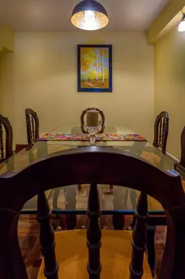 a dining room with a glass table and chairs at Katari Plaza Cusco El Virrey in Cusco