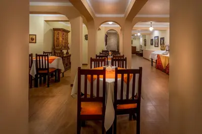 a dining room with a table and chairs and a bedroom at Katari Plaza Cusco El Virrey in Cusco