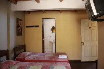 a bedroom with two beds and a bathroom at Hostal Tambo Colorado in Pisco