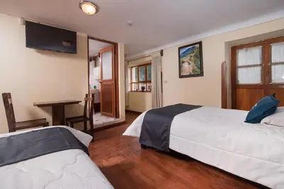 a hotel room with two beds and a television at Ayenda Casa Escondida San Cristóbal Premium in Cusco