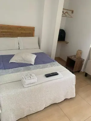 a bed with two towels and a remote control on it at Paracas Guest House in Paracas