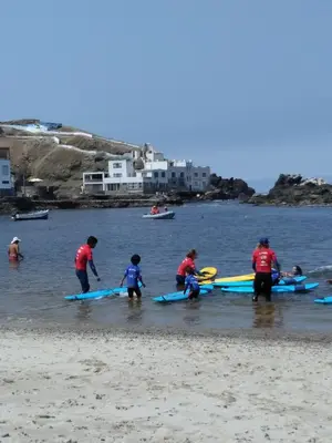 a group of people standing on a beach with surfboards at La Casa Maruja in Lima